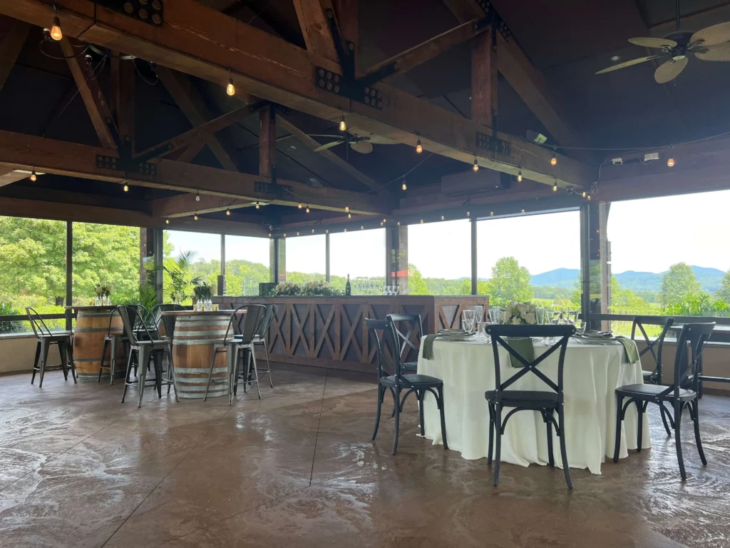 Outdoor wedding reception venue with mountain views, featuring a bar and tables set for guests.