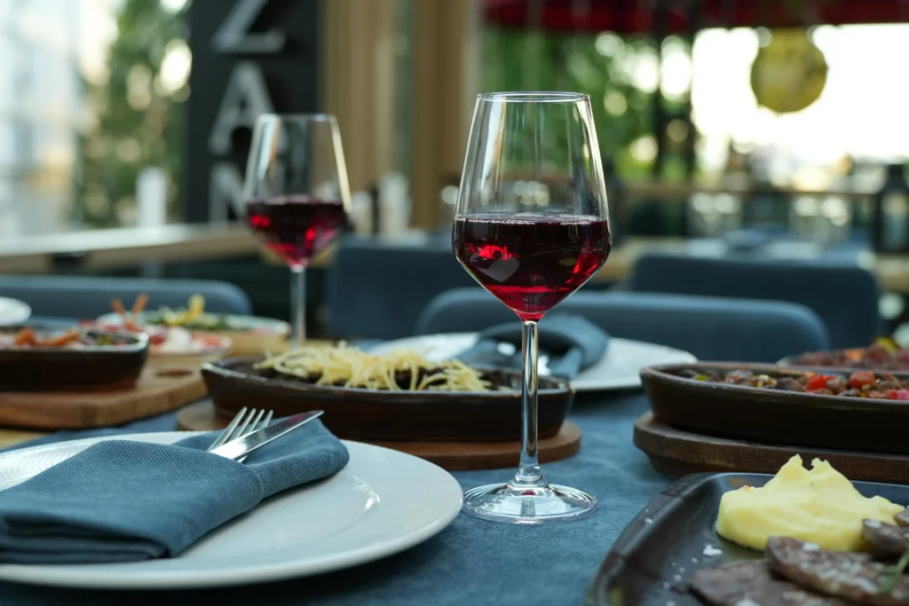 Red wine glasses on restaurant table with assorted dishes and elegant dining setup.