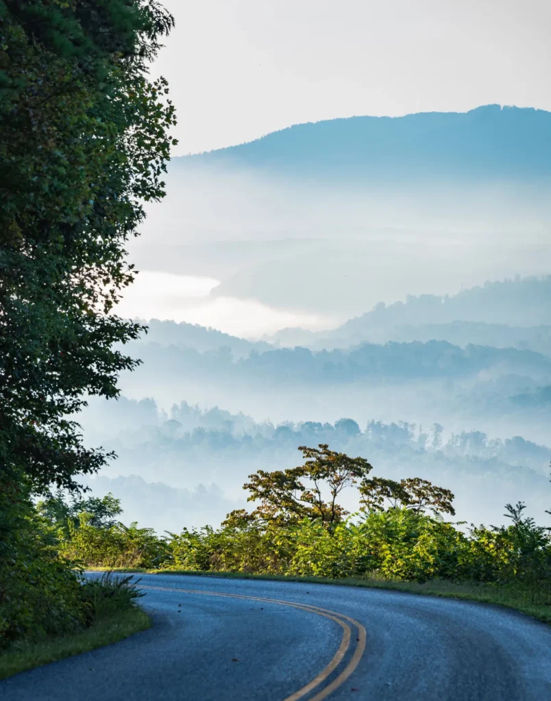 Scenic Blue Ridge Parkway overlook with misty mountain views at sunrise.