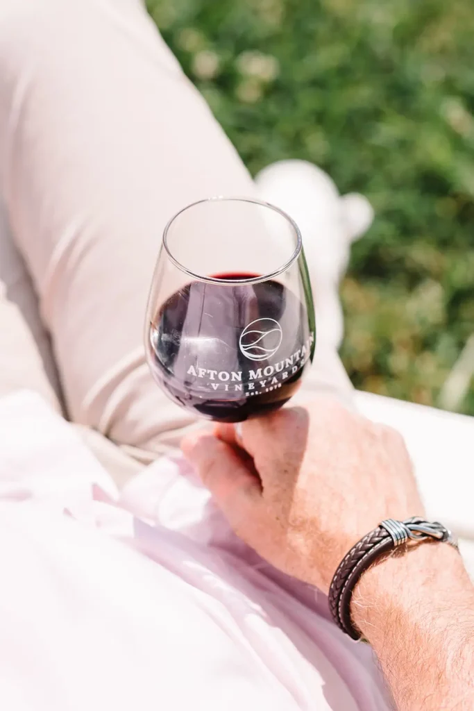 A person holding a glass of red wine with the text 